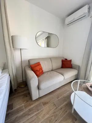 a white living room with a couch and a mirror at Appartement ensoleillé à Ajaccio in Ajaccio