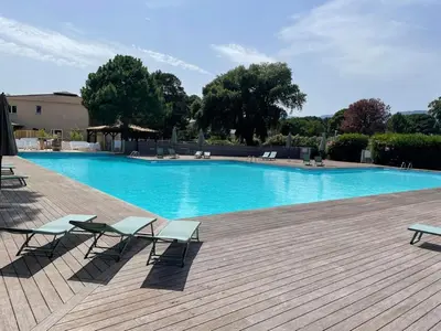 a large swimming pool with two chairs and a deck at Tamaricciu di cala rossa in Lecci