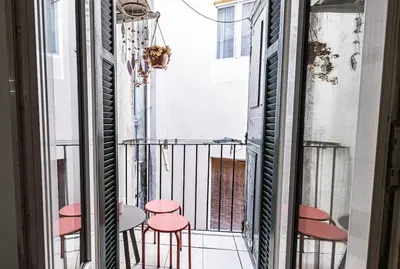a balcony with pink stools and a table at Cocooning au cœur de la cité Impériale in Ajaccio