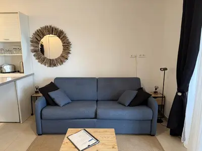 a living room with a blue couch and a mirror at Studio design front de mer classé 3 étoiles in Linguizzetta