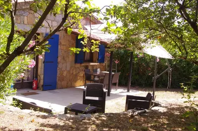 a house with a blue door and chairs and an umbrella at Meublés de Tourisme Casa Erbaggio in Sartène