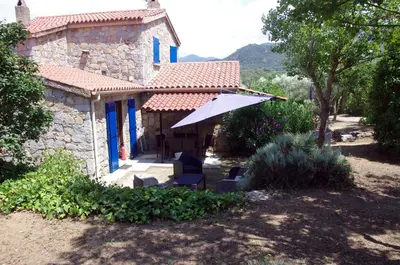 a house with two chairs and an umbrella at Meublés de Tourisme Casa Erbaggio in Sartène