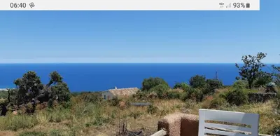 a white chair sitting on a hill next to the ocean at Cœur de village de charme in Sari Solenzara