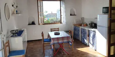 a kitchen with a table and a white refrigerator at Cœur de village de charme in Sari Solenzara