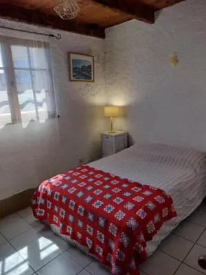 a bedroom with a bed with a red and white blanket at Cœur de village de charme in Sari Solenzara