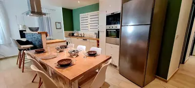 a kitchen with a table and a stainless steel refrigerator at L'alivi, Villa Prestige Avec Vue Panoramique in Figari