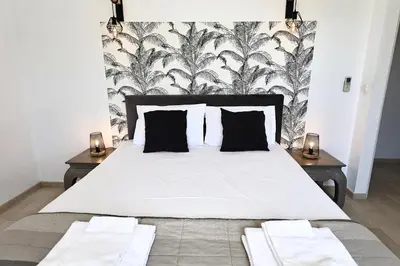 a bedroom with a large white bed with black and white wallpaper at L'alivi, Villa Prestige Avec Vue Panoramique in Figari
