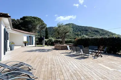 a group of chairs sitting on a wooden deck at L'alivi, Villa Prestige Avec Vue Panoramique in Figari
