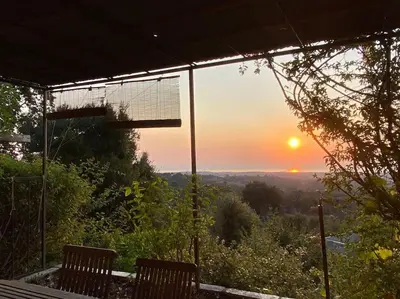 a view of the sunset from a porch with two benches at Tranquillité ,vue mer in Chiatra