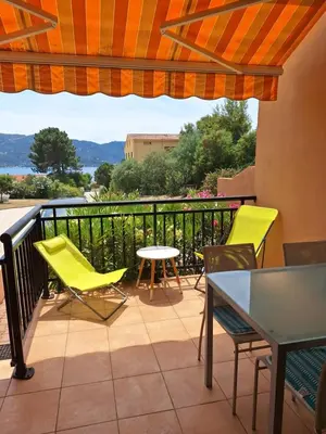 a balcony with yellow chairs and a table and a view at F2 pieds dans l'eau in Casaglione