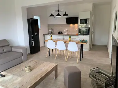 a kitchen and a living room with a table and white chairs at L'alivu di porto vecchio*** ( piscine chauffée ) in Porto-Vecchio