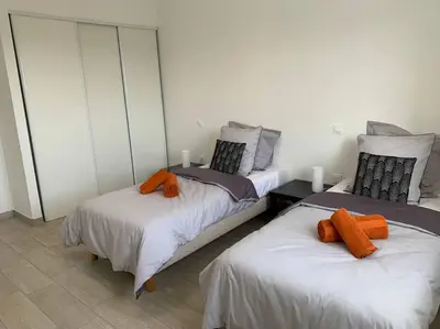 two beds with orange pillows on them in a room at L'alivu di porto vecchio*** ( piscine chauffée ) in Porto-Vecchio