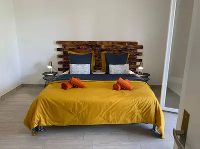 a large yellow bed with orange pillows on it at Caminu di porto vecchio***. (Piscine chauffée ) in Porto-Vecchio