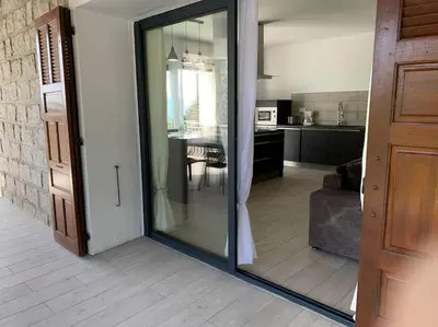 a sliding glass door in a living room with a kitchen at Caminu di porto vecchio***. (Piscine chauffée ) in Porto-Vecchio