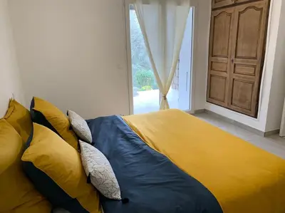 a bed with yellow and blue sheets in a bedroom at Caminu di porto vecchio***. (Piscine chauffée ) in Porto-Vecchio