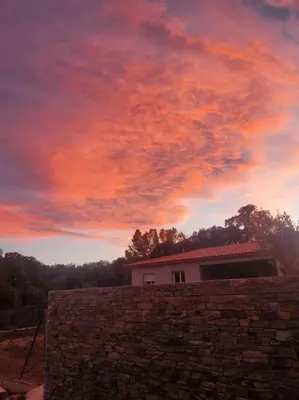 a sunset over a brick wall and a building at Casa di l Alivetu in Ventiseri