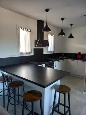a kitchen with a black counter top and two stools at Casa di l Alivetu in Ventiseri