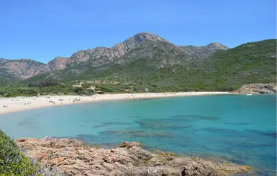a beach with people in the water and mountains at 3 Bedroom Stunning Home In Marignana in Marignana