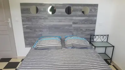 a bed with two pillows and a wooden wall at maison T3 500m de la plage in Poggio-Mezzana