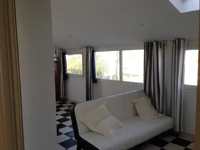 a living room with a white couch and two windows at maison T3 500m de la plage in Poggio-Mezzana