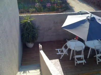 a patio with an umbrella and a table and chairs at maison T3 500m de la plage in Poggio-Mezzana