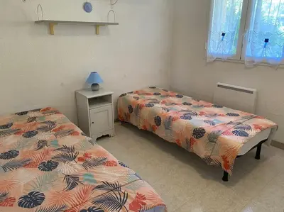 a bedroom with two beds and a table with a lamp at Charmant bonheur en bord de mer in Ghisonaccia