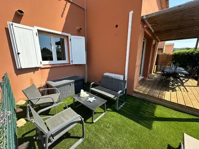 a patio with chairs and a table on the grass at Mini Villa 4-6 pers. Les hameaux de Saint Cyprien in Lecci