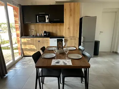 a kitchen with a wooden table and chairs and a kitchen with a table at Mini Villa 4-6 pers. Les hameaux de Saint Cyprien in Lecci