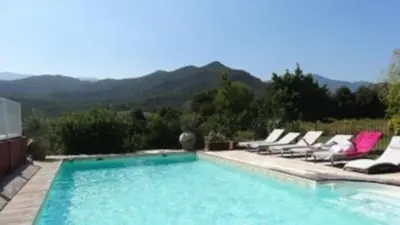 a swimming pool with lounge chairs and mountains in the background at Villa E case di u Puntale in Ghisonaccia