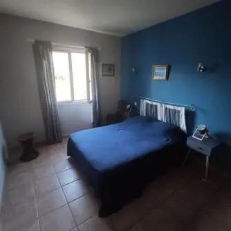 a blue bedroom with a bed and a window at Villa E case di u Puntale in Ghisonaccia