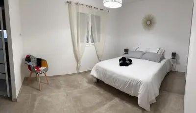 a white bedroom with a white bed and a chair at Villa pedicervu haut in Ventiseri
