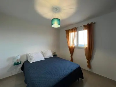 a bedroom with a blue bed and a window at Villa pedicervu haut in Ventiseri