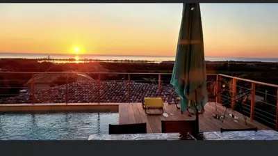 a patio with an umbrella and a pool with a sunset at Villa pedicervu haut in Ventiseri