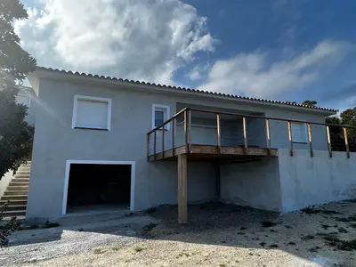 a white house with a deck on top of it at Villa pedicervu haut in Ventiseri