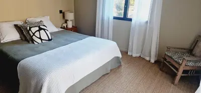a bedroom with a bed and a chair and a window at VILLA AVEC PISCINE PORTO-VECCHIO CORSICA in Porto-Vecchio
