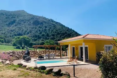 a small yellow house with a pool in front of a mountain at Très belle villa au calme avec piscine à Sagone in Sagone