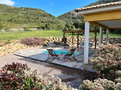 a patio with a table and chairs and a pool at Très belle villa au calme avec piscine à Sagone in Sagone