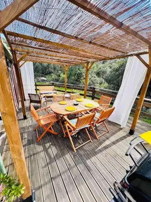 a wooden table and chairs on a wooden deck at Chalet au calme à Sagone en Corse in Sagone
