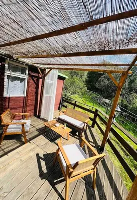 a wooden deck with chairs and a table and a pergola at Chalet au calme à Sagone en Corse in Sagone