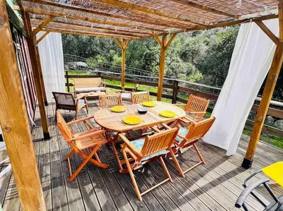 a wooden table and chairs on a deck at Chalet au calme à Sagone en Corse in Sagone