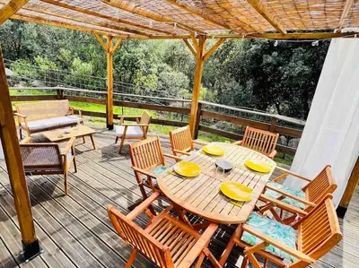 a wooden table and chairs on a deck at Chalet au calme à Sagone en Corse in Sagone