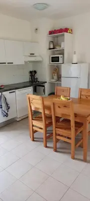 a kitchen with a wooden table and chairs at Location appartement les pieds dans l'eau, Résidence Aqua Linda à Poggio-Mezzana in Poggio-Mezzana