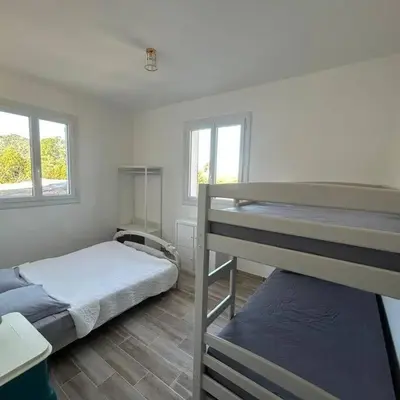 a bedroom with two bunk beds and two windows at Appartement entre mer et montagne avec beau jardin in Calenzana