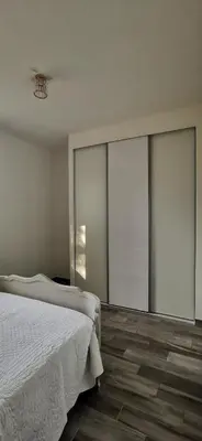 a bedroom with a white bed and glass walls at Appartement entre mer et montagne avec beau jardin in Calenzana