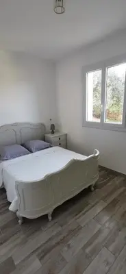 a white bedroom with a bed and two windows at Appartement entre mer et montagne avec beau jardin in Calenzana