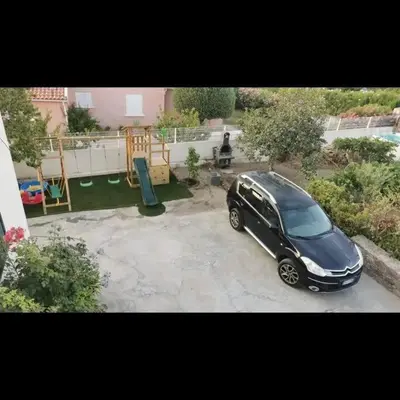 a black car parked in a driveway in a yard at Appartement entre mer et montagne avec beau jardin in Calenzana