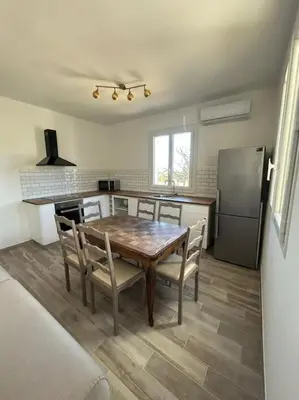 a kitchen with a table and chairs and a refrigerator at Appartement entre mer et montagne avec beau jardin in Calenzana