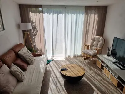 a living room with a couch and a table and a tv at Villa les pieds dans l'eau résidence calme in Poggio-Mezzana
