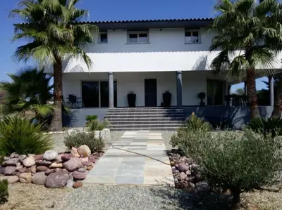 a house with palm trees in front of it at Appartement de détente et vue sur montagnes in Ghisonaccia