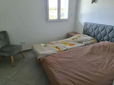 a bedroom with a bed and a chair and a window at Appartement de détente et vue sur montagnes in Ghisonaccia
